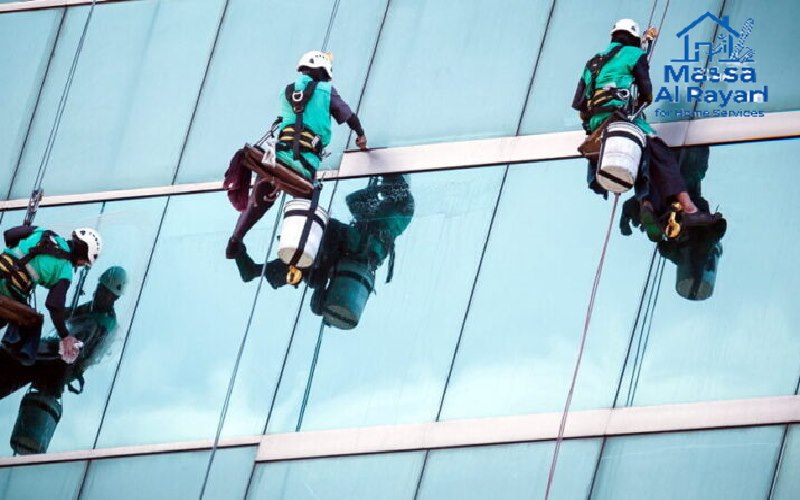 صورة عمال على حبال ينظفون واجهة زجاجية