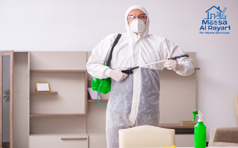 رجل أمن وسلامة يرتدي معدات الوقاية الشخصية (قفازات وقناع) أثناء رش مبيد حشري صديق للبيئة في زاوية منزل.
